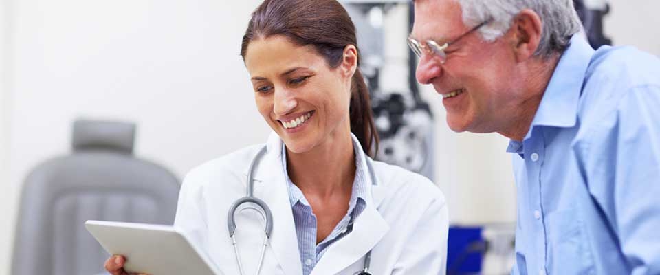 An older man and young female doctor review the results of an eye exam.