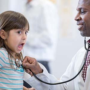 A little girl is surprised by the cold touch of the doctor's stethoscope.