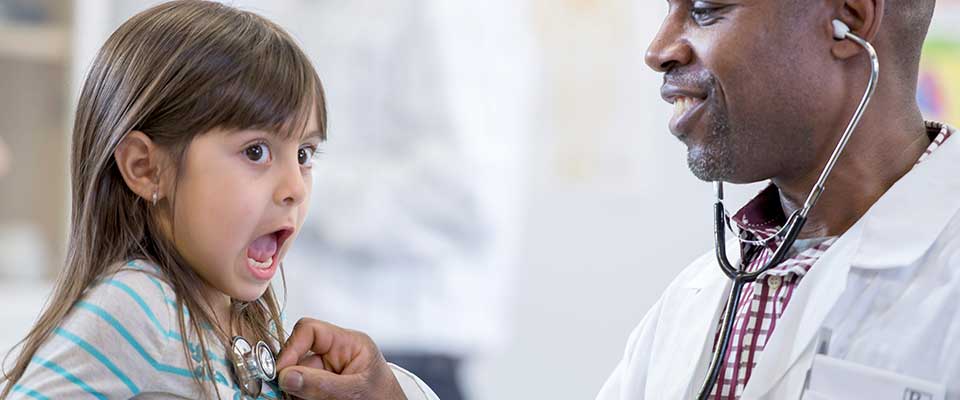 A little girl is surprised by the cold touch of the doctor's stethoscope.