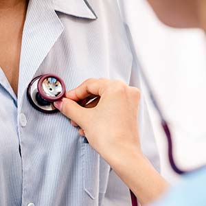 A doctor at a Centers of Excellence-approved facility listens to her patient's heartbeat with a stethoscope.