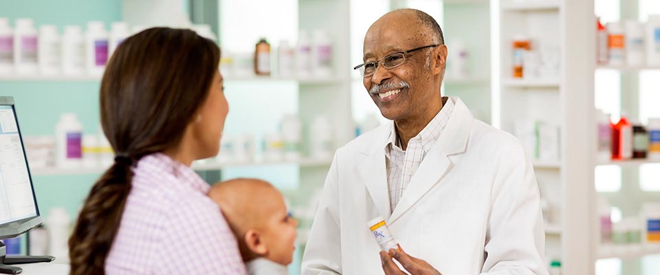 A smiling doctor explains the overuse of antibiotics to a mother and her child.