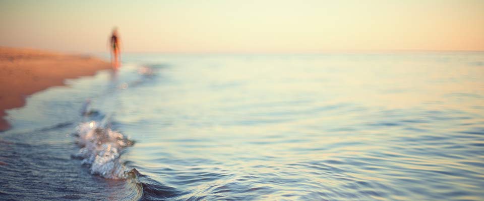 A blurred figure walks along the beach at sunset as he considers how to relieve anxiety.