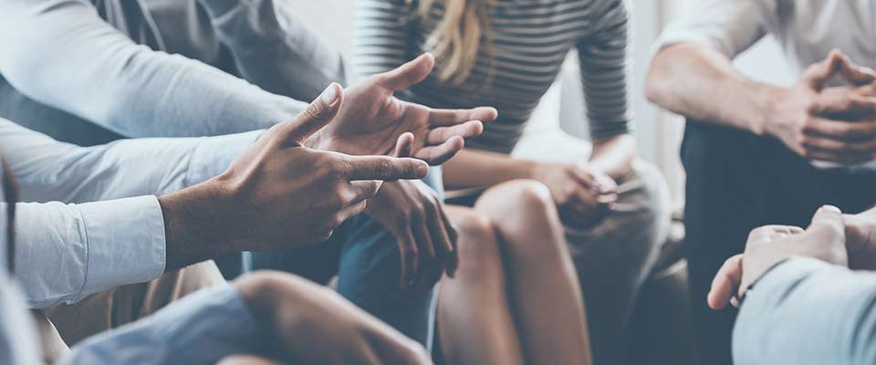 Several friends sit on the couch while discussing their high-deductible health plans.