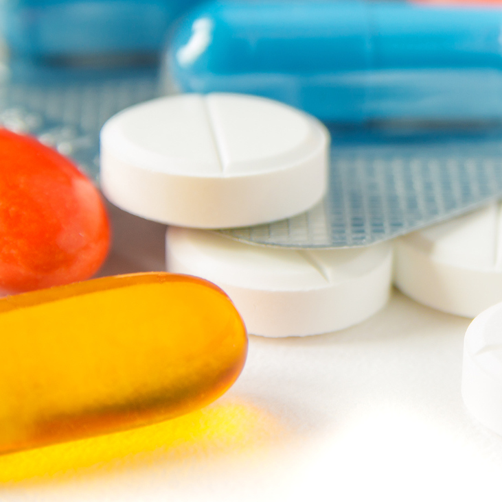 A photo white, orange, and yellow prescription pills used to represent a pharmacy benefits manager.