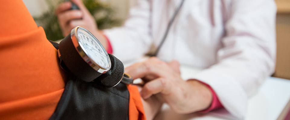 A doctor measures his patient's blood pressure, as part of a company's biometric screening initiative.