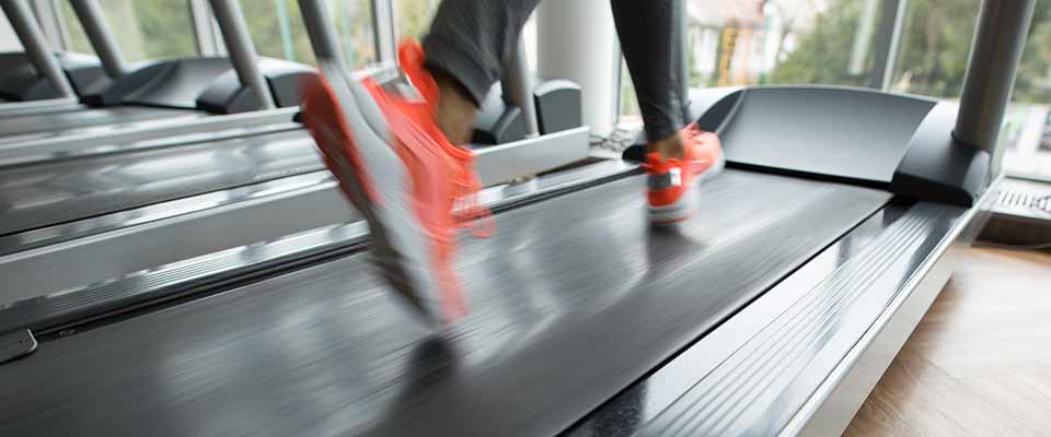 A woman in a blurred photograph runs on a treadmill, hitting her daily HIIT goals.