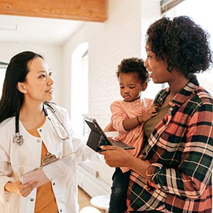 Woman with her child at a medical office consults a list of questions to ask her doctor.