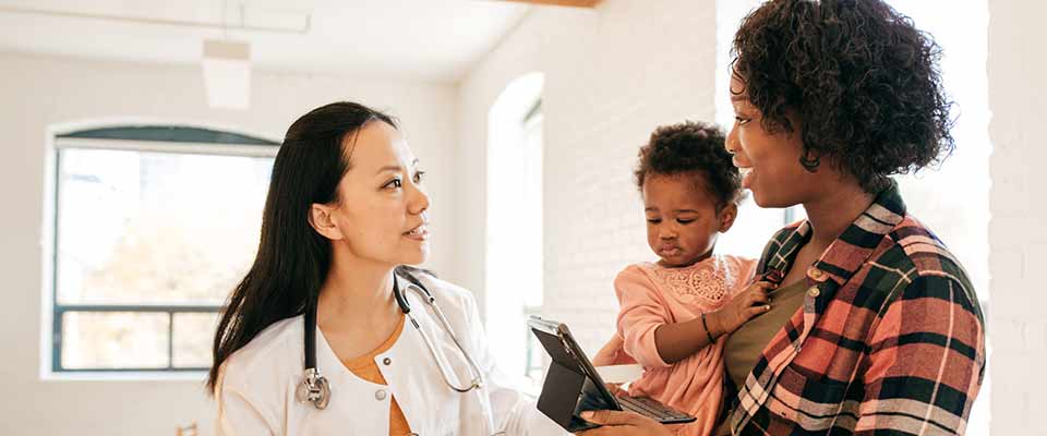 Woman with her child at a medical office consults a list of questions to ask her doctor.