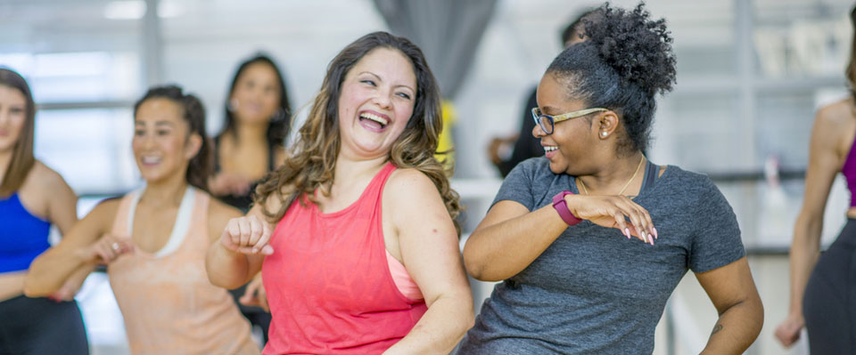 A group of women in a fitness studio are pictured exercising together and having fun.