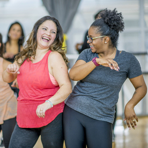 A group of women in a fitness studio are pictured exercising together and having fun.