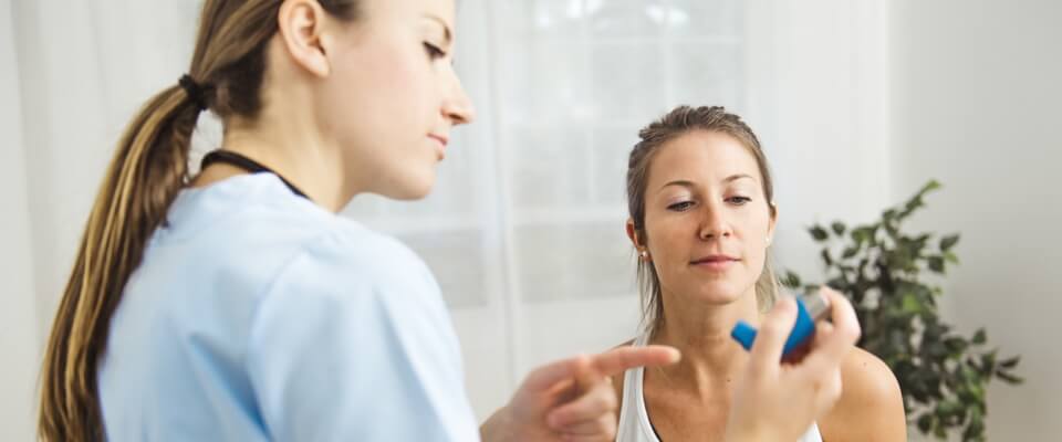 Nurse instructing woman with inhaler