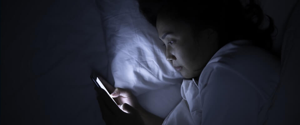Woman using phone in bed