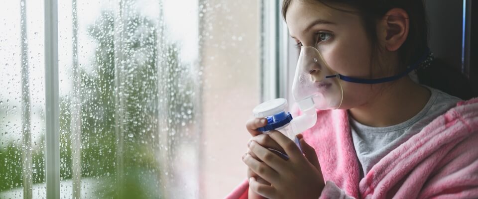 Girl with respirator staring out rainy window