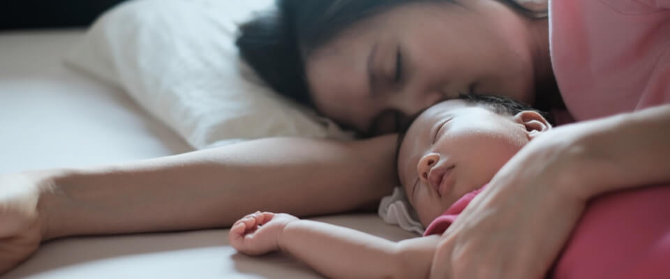 Mom sleeping with baby on bed