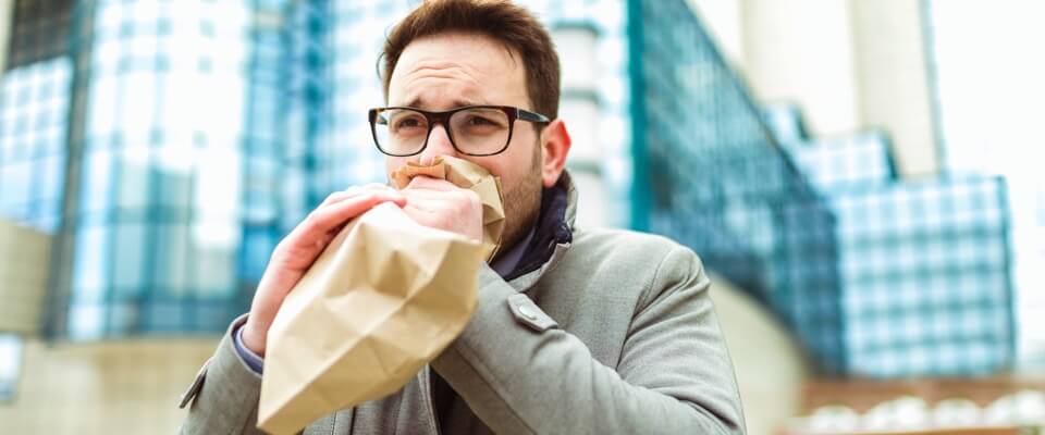 Man with glasses breathing into open bag