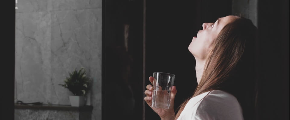 Girl holding a water glass and gargling.