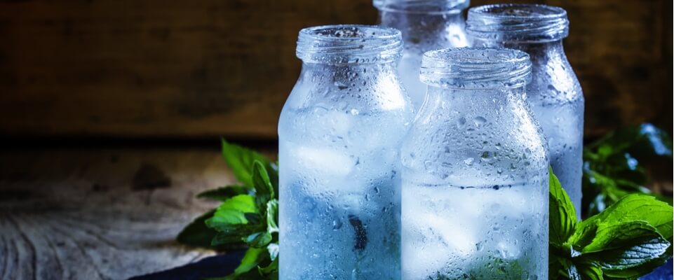 Four glass bottles of water with ice.