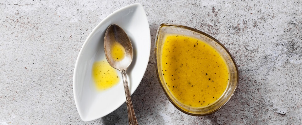 Salad dressing next to a plate and a spoon.