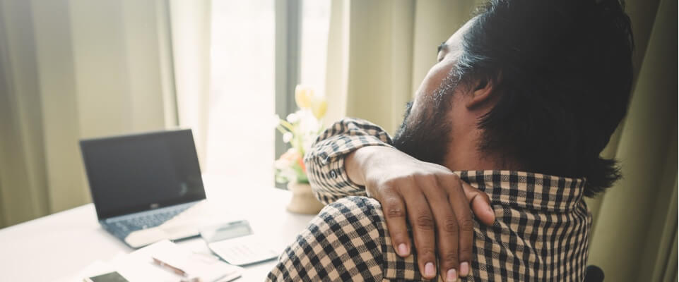 Man sitting with shoulder pain at work